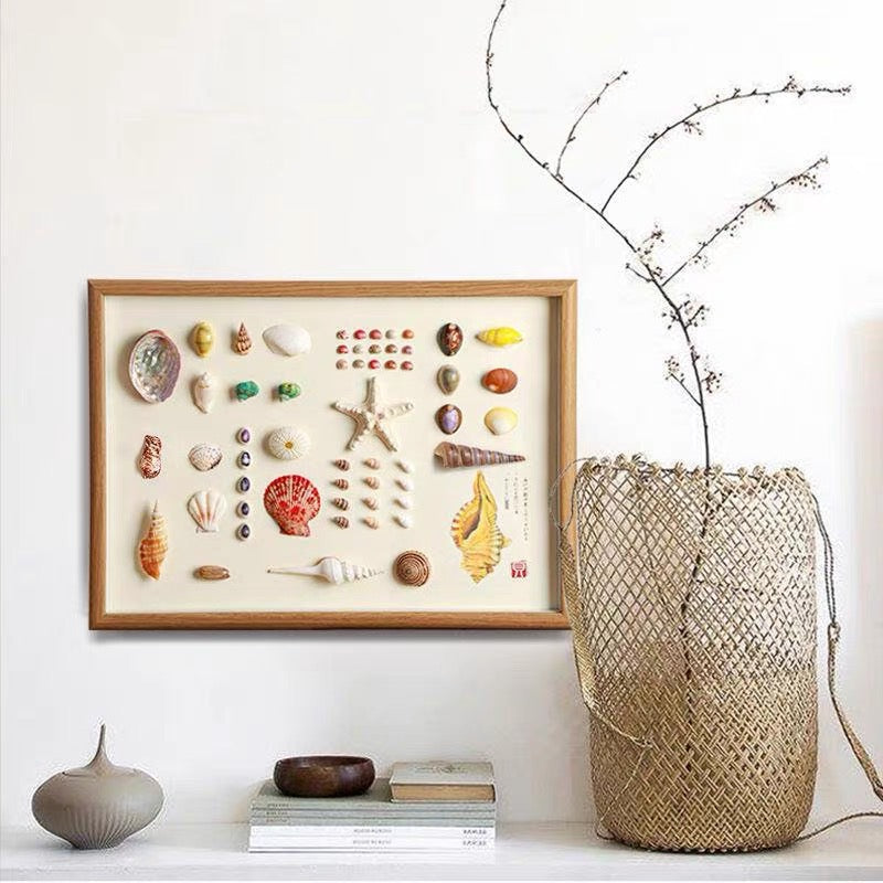Framed natural shell and starfish collection display art in oak wood frame, mounted on white wall with woven basket decor